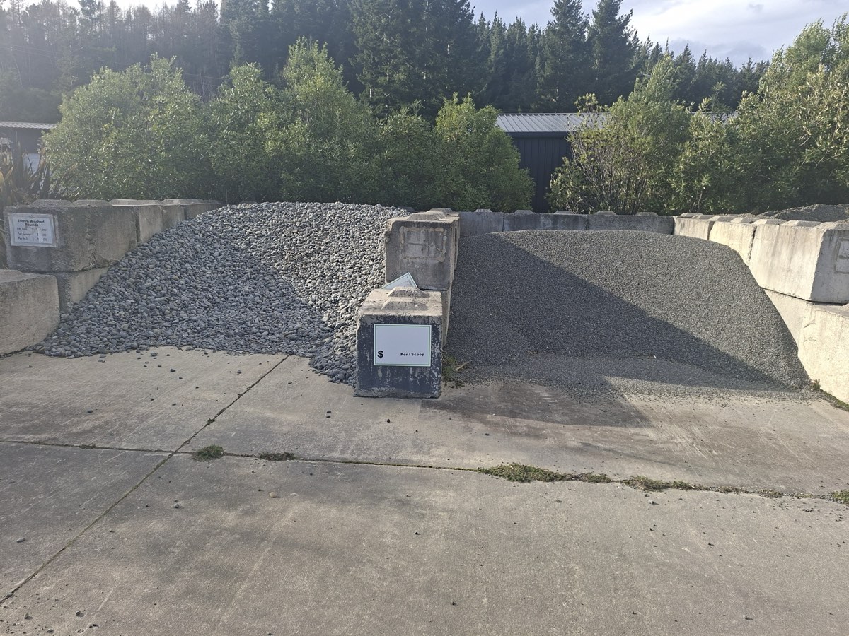 Pea metal and screened stone piles with price sign